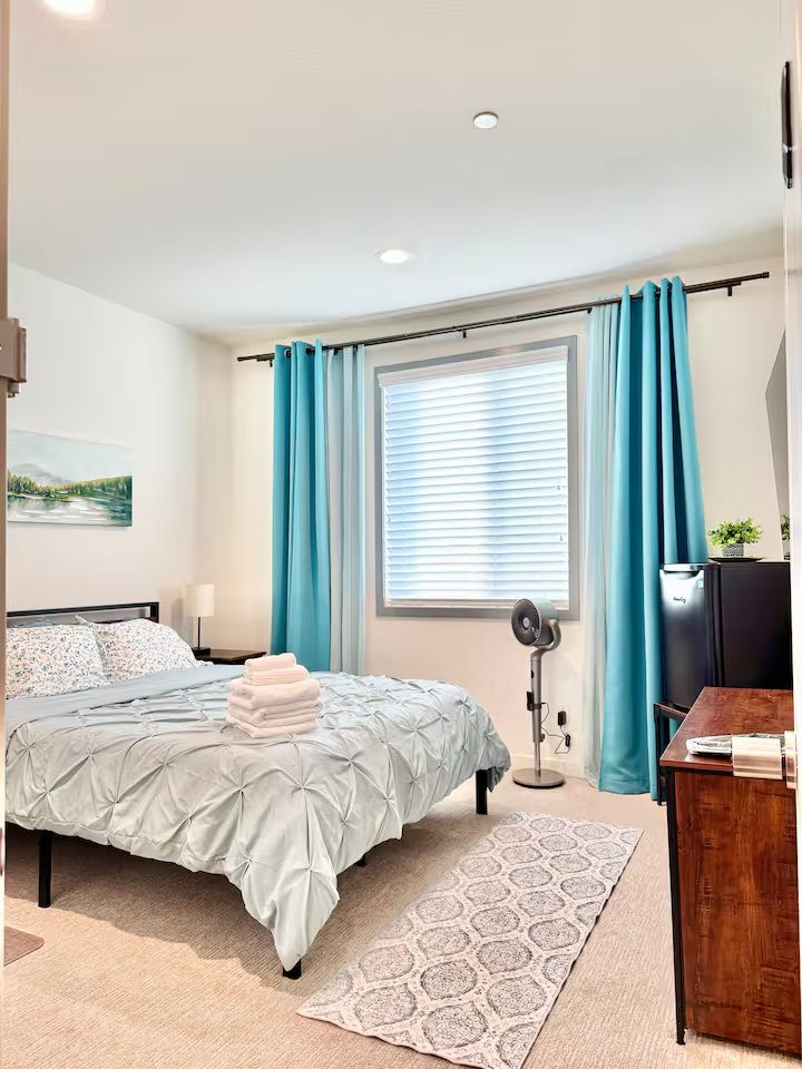 Opal queen bed with pale bedding and teal curtains