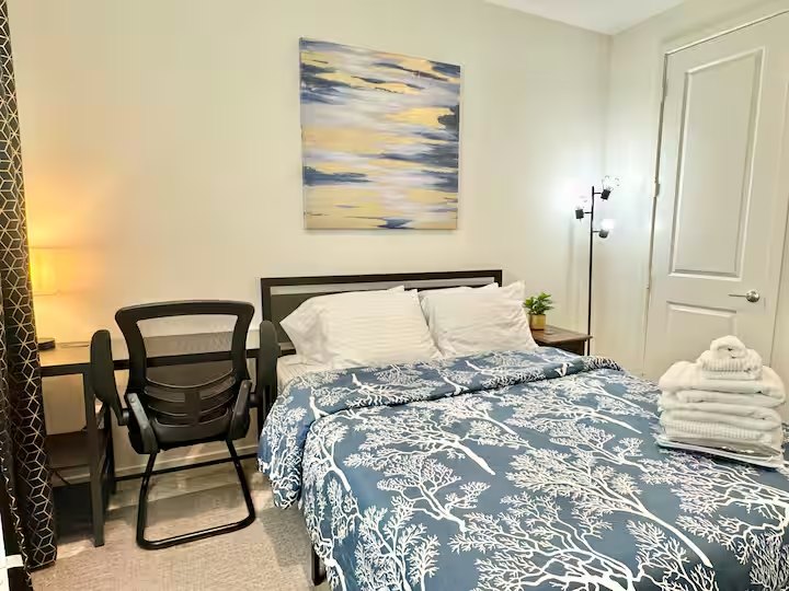 Diamond bedroom with blue patterned bedding and a desk beside the window