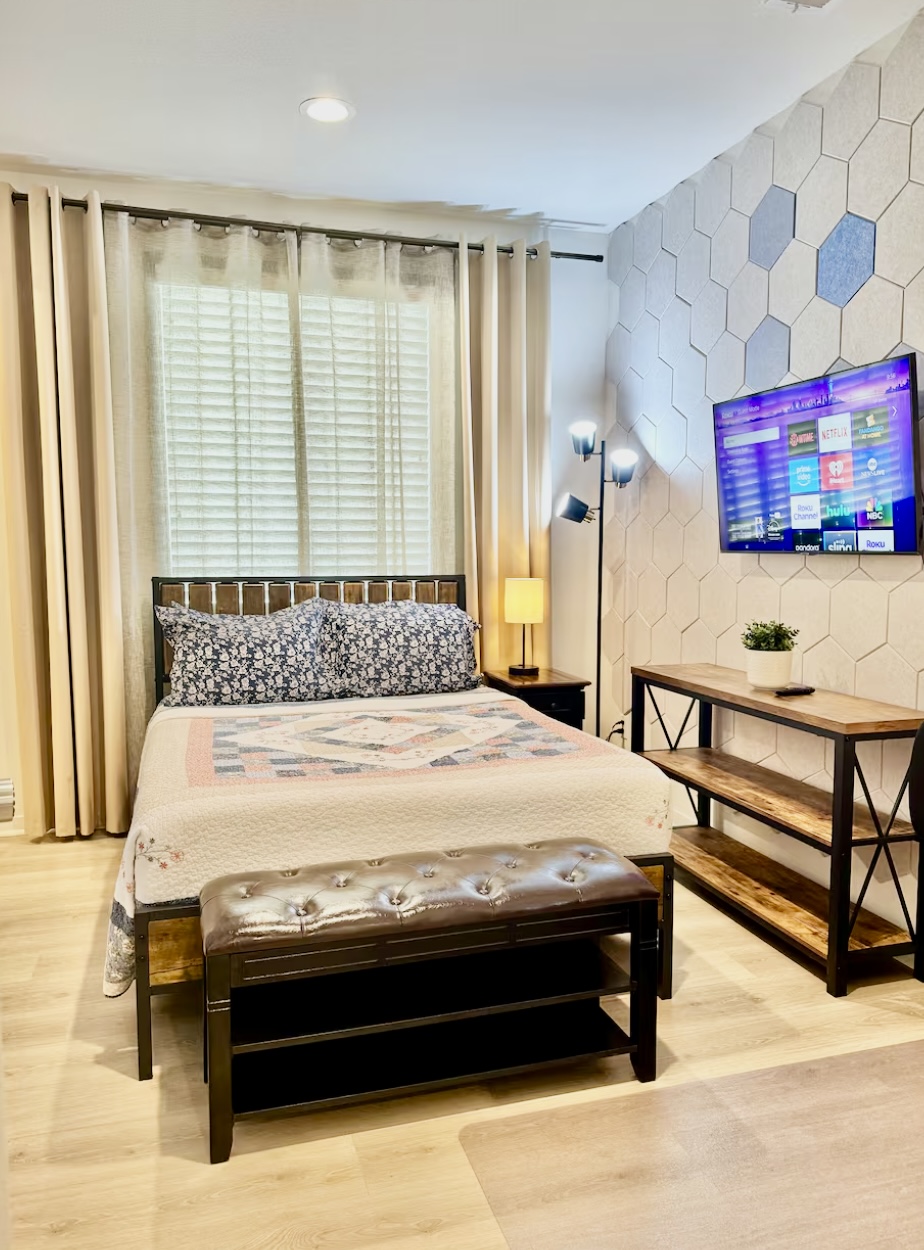 Sapphire bedroom with double bed, upholstered bench, television, and geometric accent wall